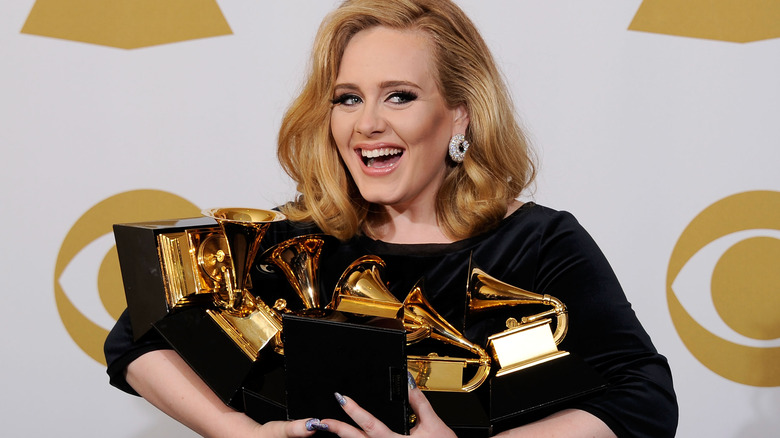 Adele holding her many Grammy awards