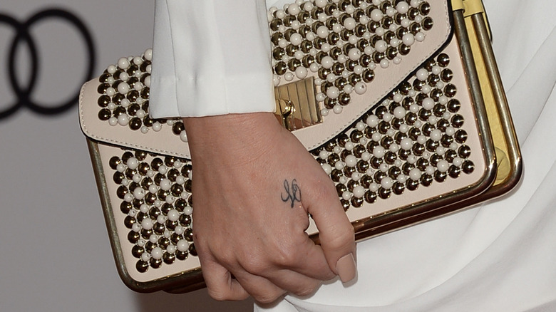 Kardashian's "LO" tattoo is visible as she holds a purse