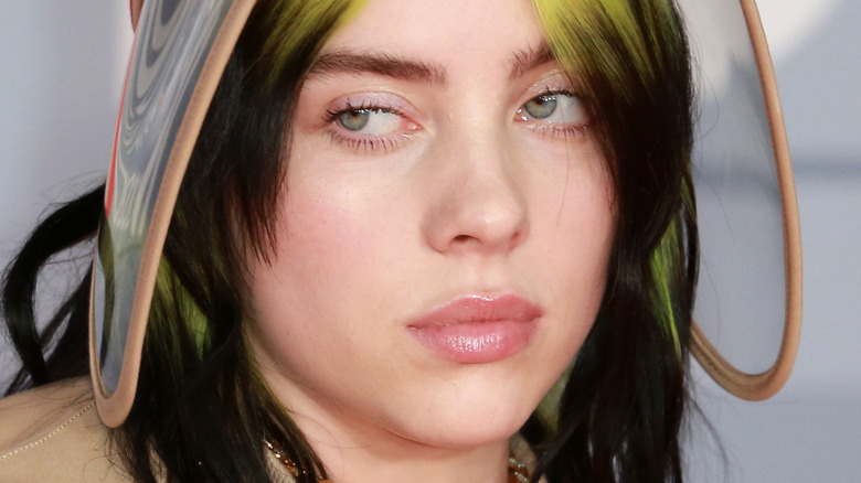 Billie Eilish with green hair and visor looking to side