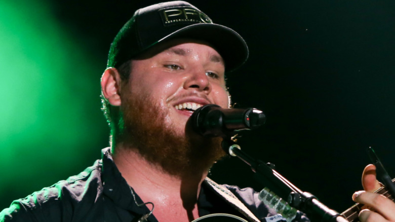 Luke Combs performing and smiling