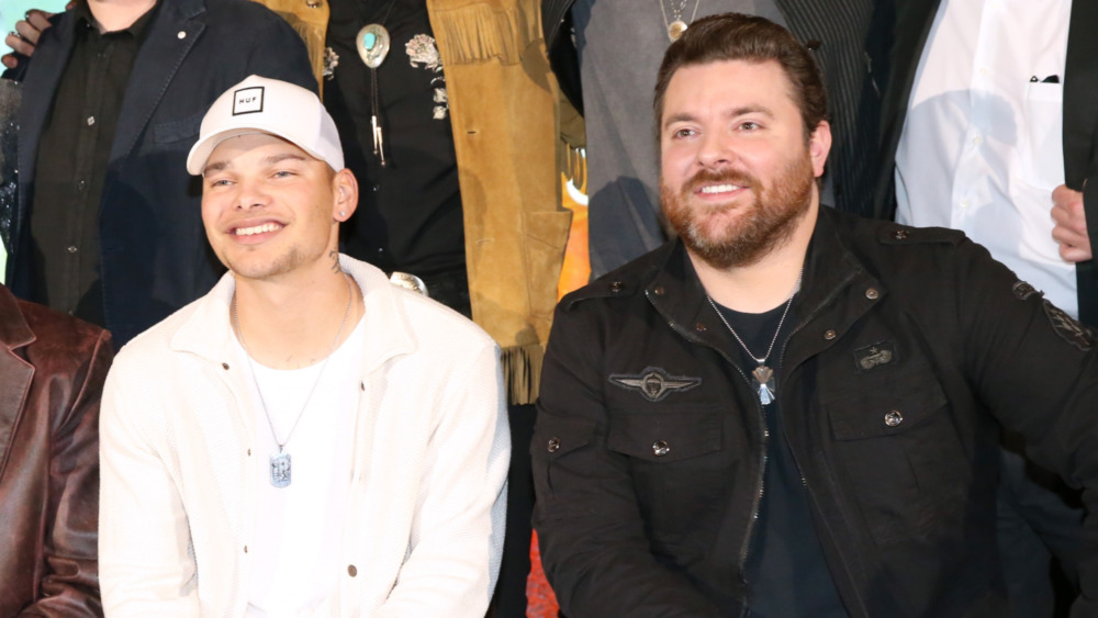 Kane Brown and Chris Young smile together while posing at an event