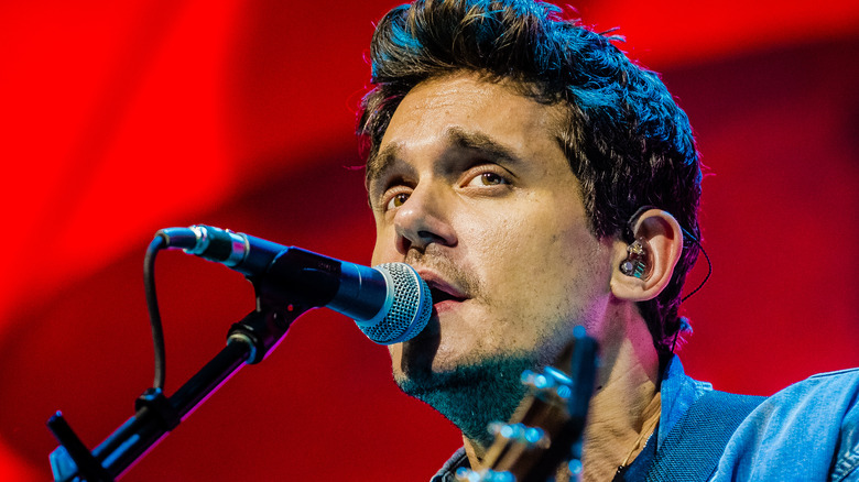 John Mayer sings into a microphone on stage
