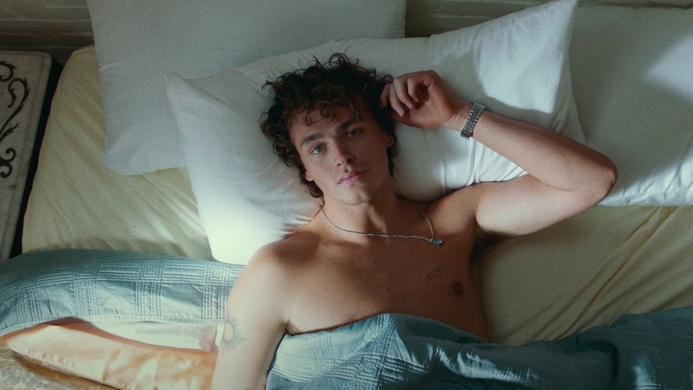 Jonah Marais lying in bed in the music video for "Lotus Inn"