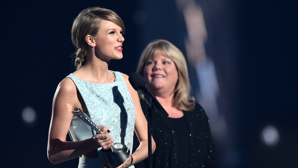 Taylor Swift holds an award statue while her mom Andrea Swift looks on