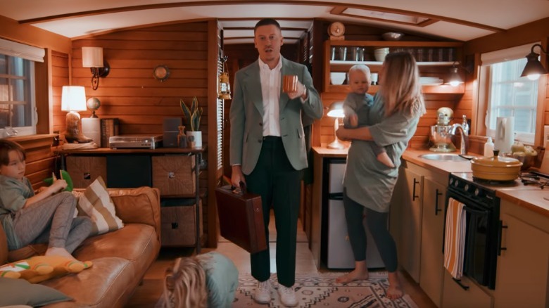 Macklemore in carries a cup and suitcase in his Next Year music video