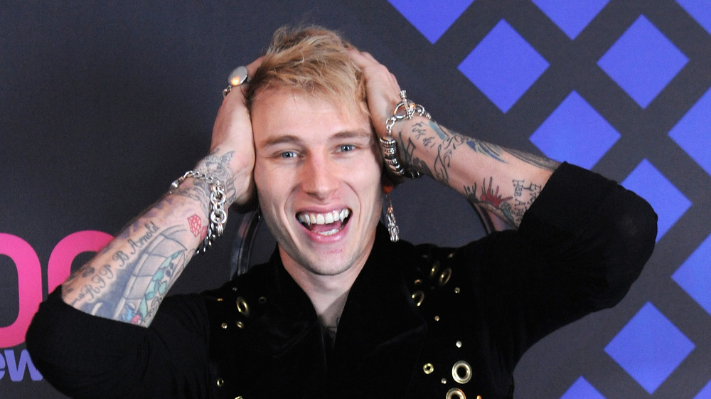 Machine Gun Kelly with his hands on his head