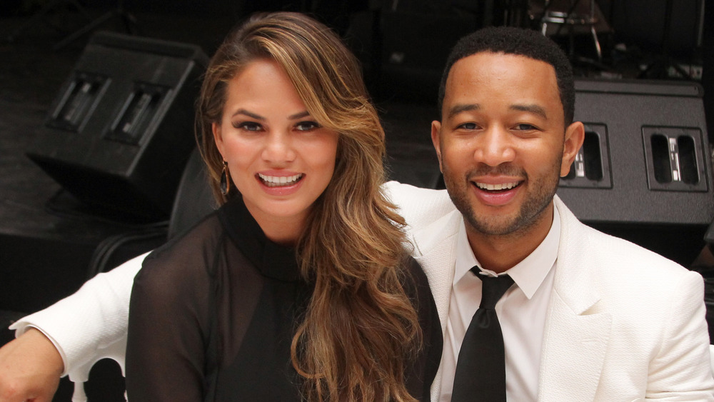 John Legend and Chrissy Teigen sitting at a table 