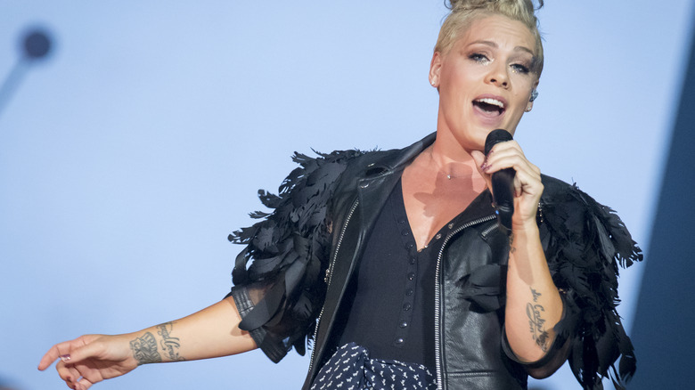 Pink holding arm out while singing