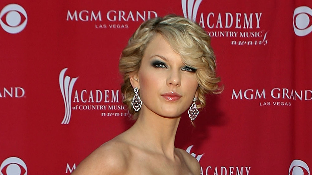 Taylor Swift purses her lips while posing on the red carpet at the ACMs