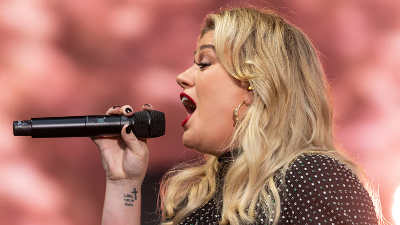 Kelly Clarkson on-stage singing into a microphone
