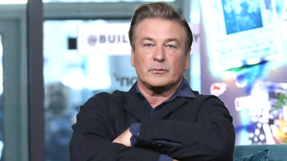 Alec Baldwin sits with his arms crossed