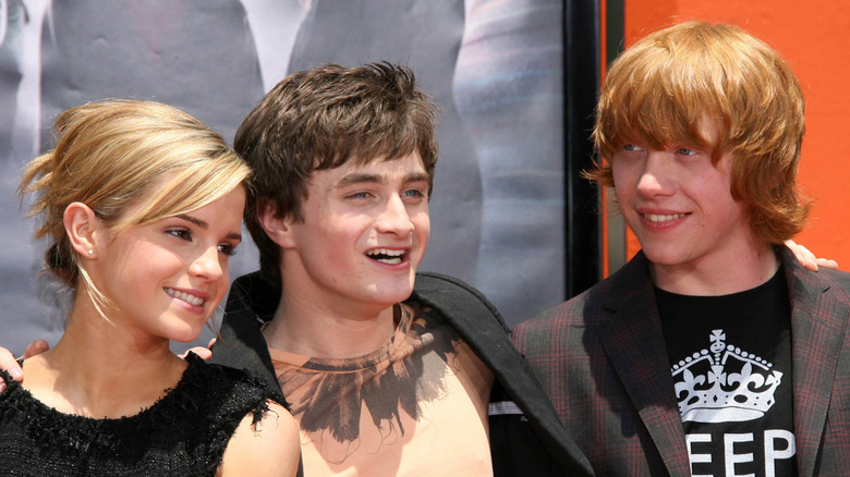 Daniel Radcliffe, Emma Watson and Rupert Grint embrace at an event