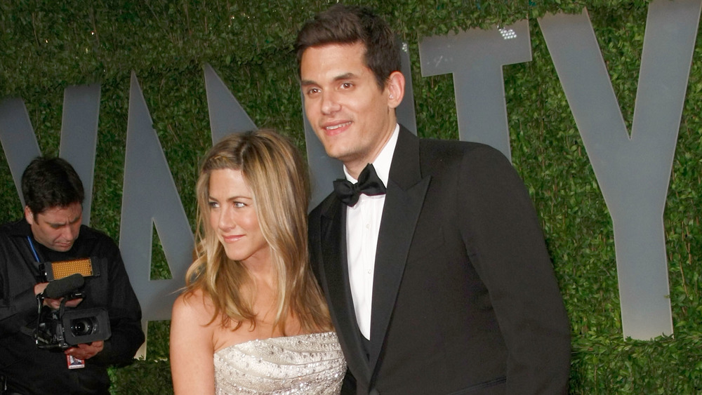 Jennifer Aniston and John Mayer smiling while posing arm in arm on the red carpet