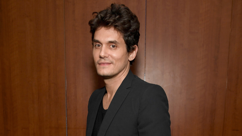 John Mayer posing from the side with a smirk