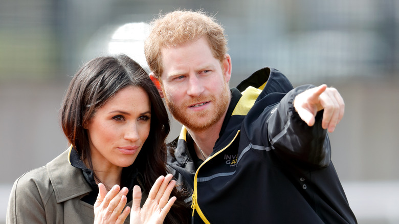 Prince Harry pointing while Meghan Markle watches