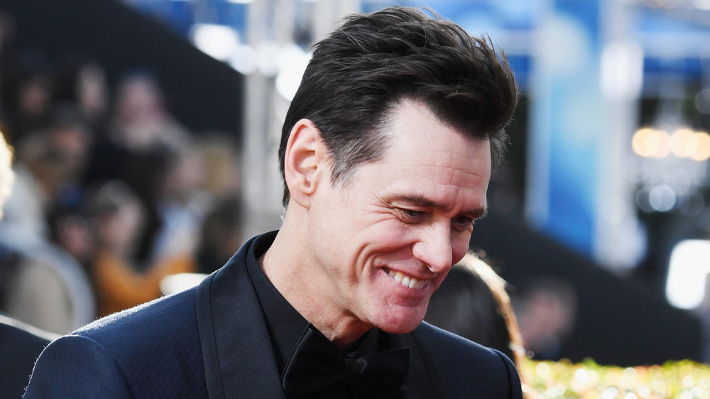 Jim Carrey smiling, looking down 