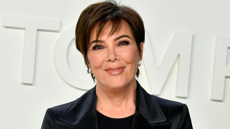 Kris Jenner in a black suit on a white background