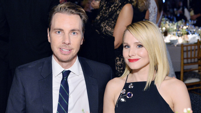 Dax Shepard and Kristen Bell sitting at a table next to each other and smiling