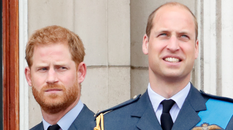 Prince Harry looking serious and Prince William smiling