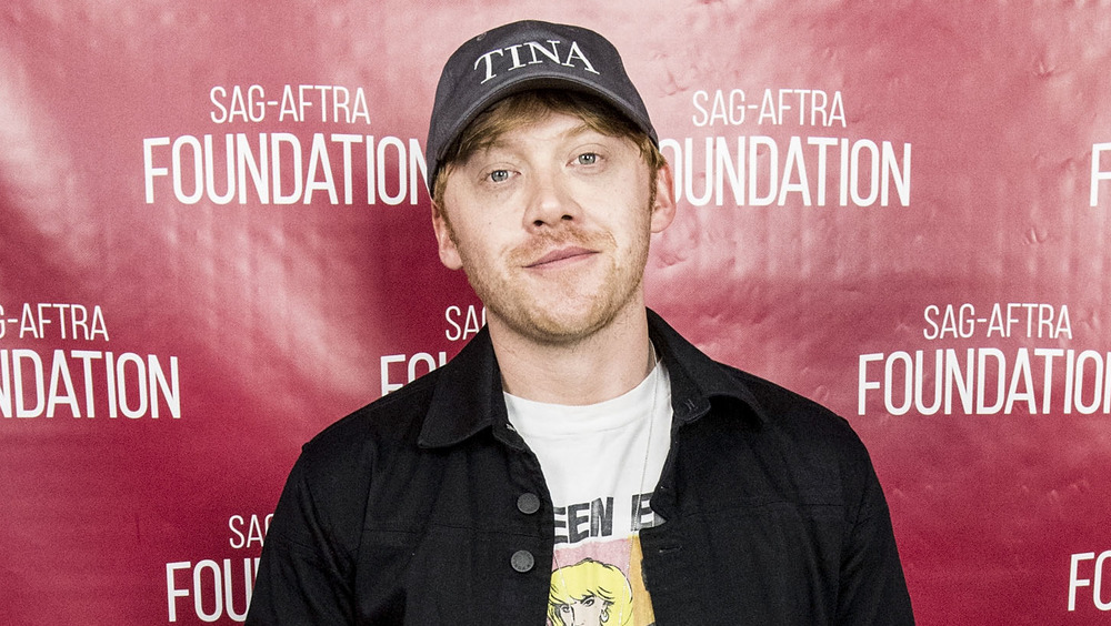 Rupert Grint wears a baseball hat while posing at an event