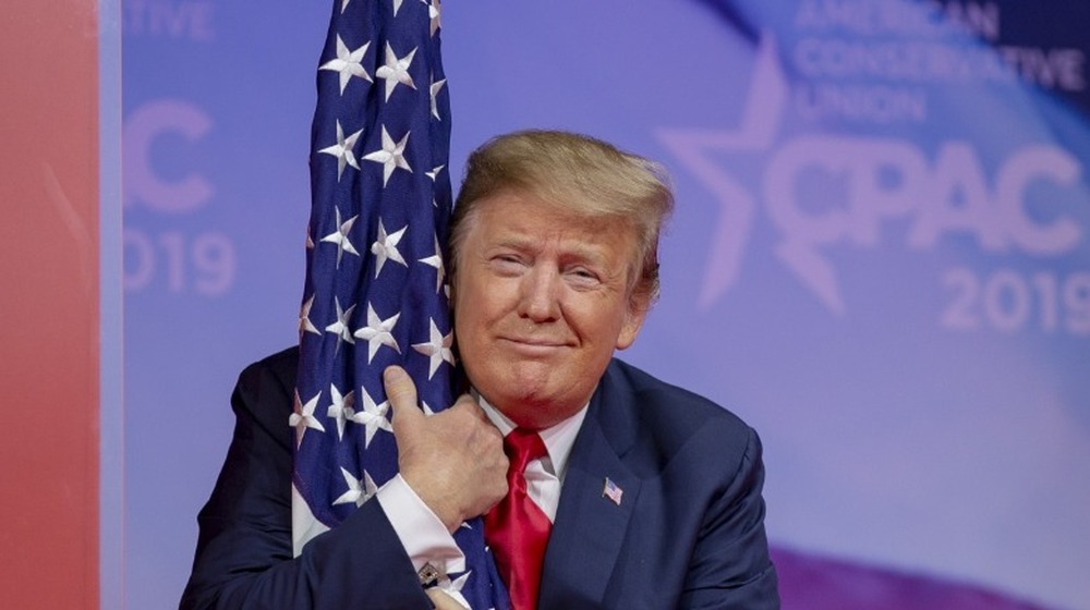 U.S. President Donald Trump hugs the U.S. flag during CPAC 2019 on March 02, 2019