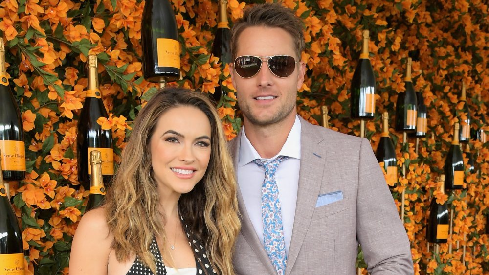 Chrishell Stause, Justin Hartley posing in front of wine bottles and flowers