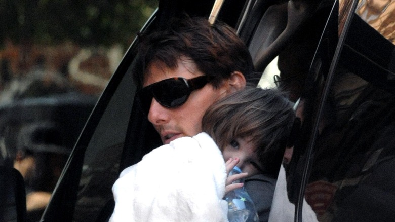 Tom Cruise holding Suri, taking her out of car