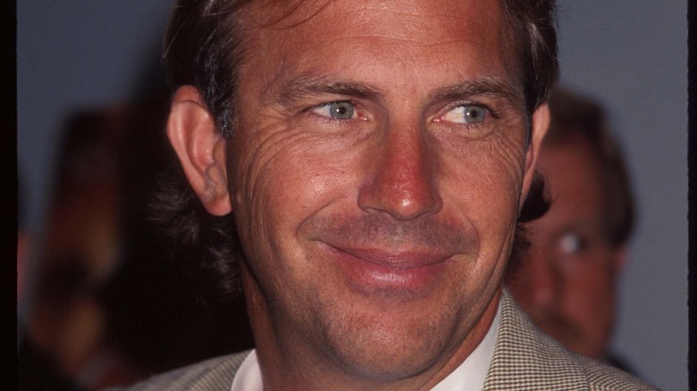 Kevin Costner smiles in a tan suit