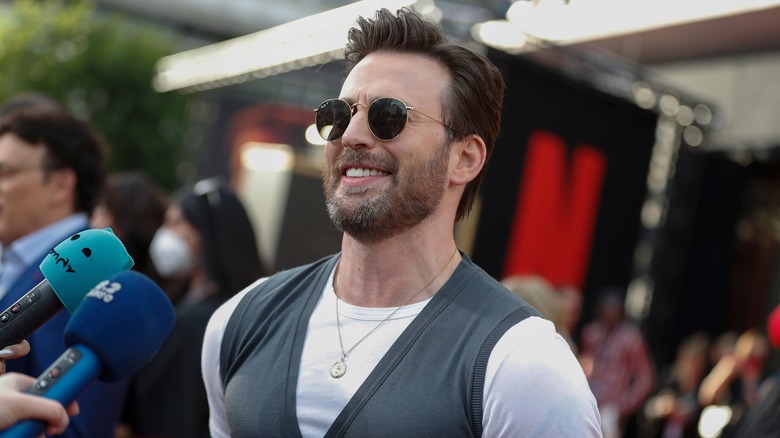 Chris Evans smiling in front of microphones on red carpet