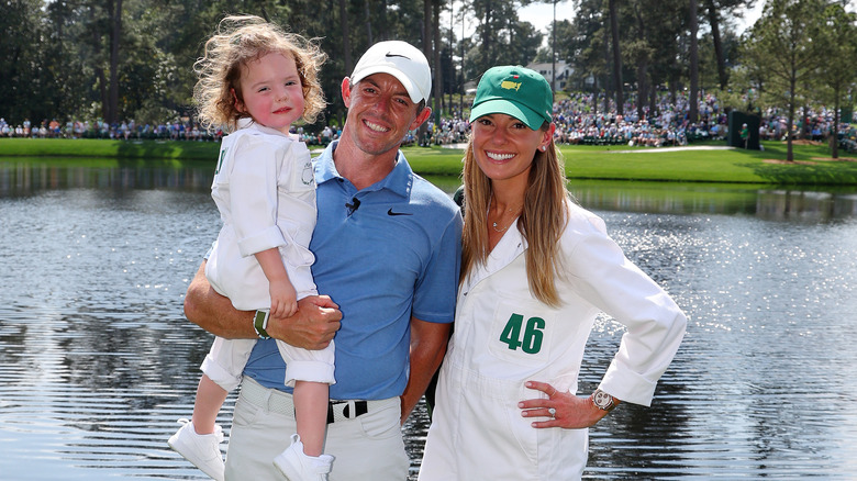 Rory McIlroy and Erica Stoll posing with child