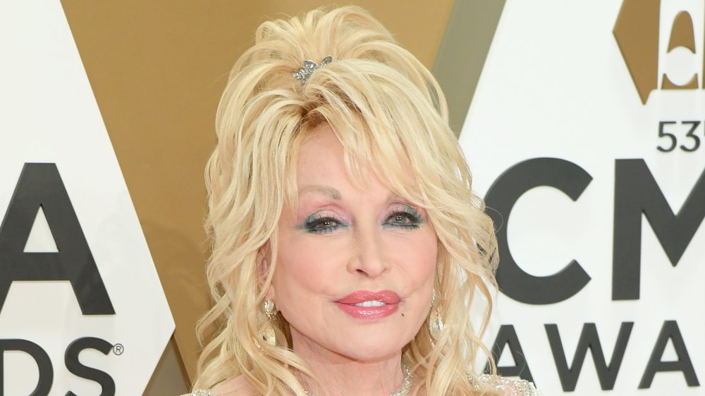 Dolly Parton in a white sparkly dress, posing at the CMA Awards