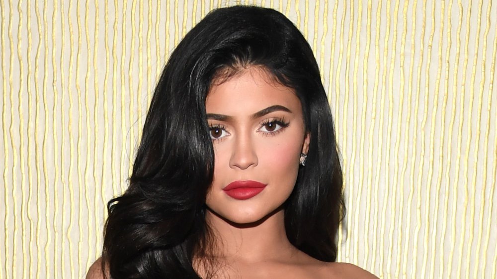 Kylie Jenner in a red dress, posing with a neutral expression