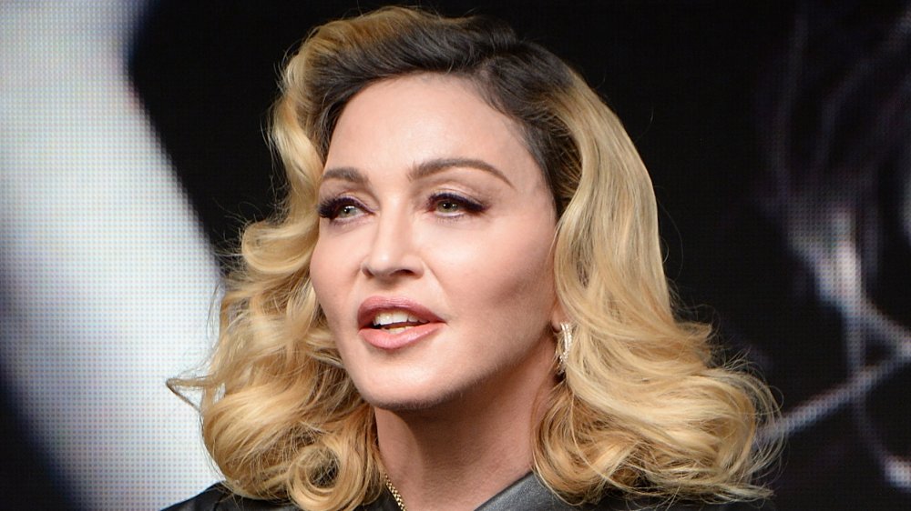 Madonna in a black leather outfit, speaking while looking off to the side