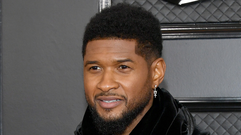 Usher smiles in front of black backdrop