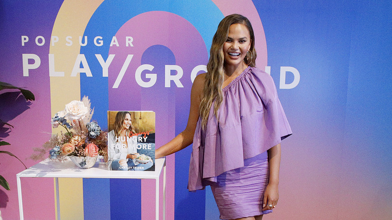 Chrissy Teigen posing with cookbook