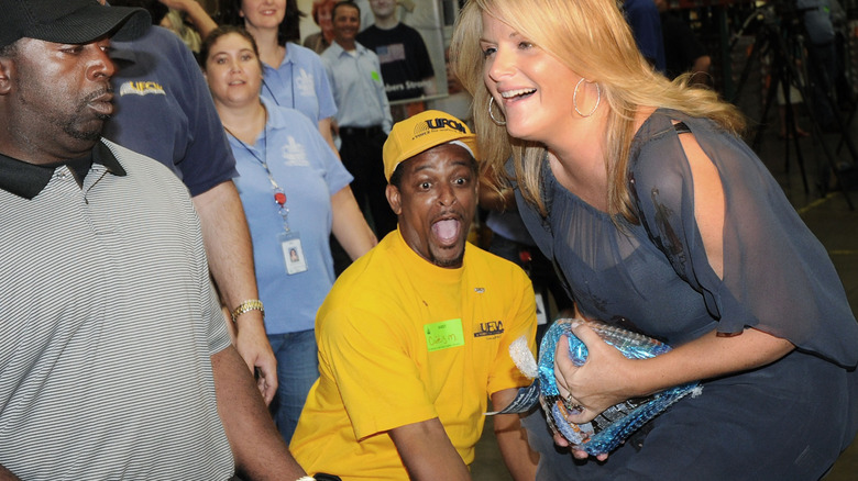 Trisha Yearwood catches a frozen turkey while volunteering with Second Harvest Food Banks in 2010 with Paula Deen.