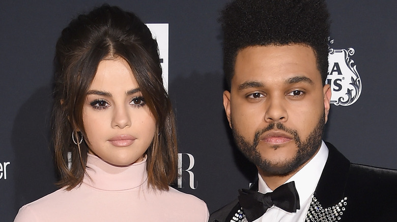 Selena Gomez and The Weeknd posing not smiling