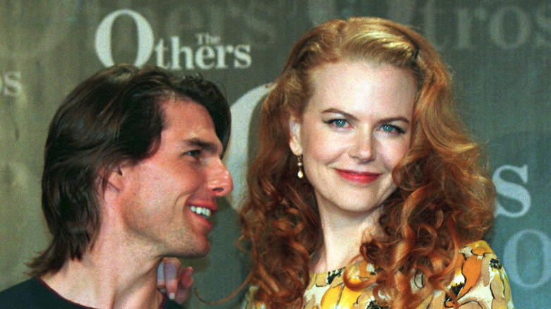 Tom Cruise whispering to smiling Nicole Kidman