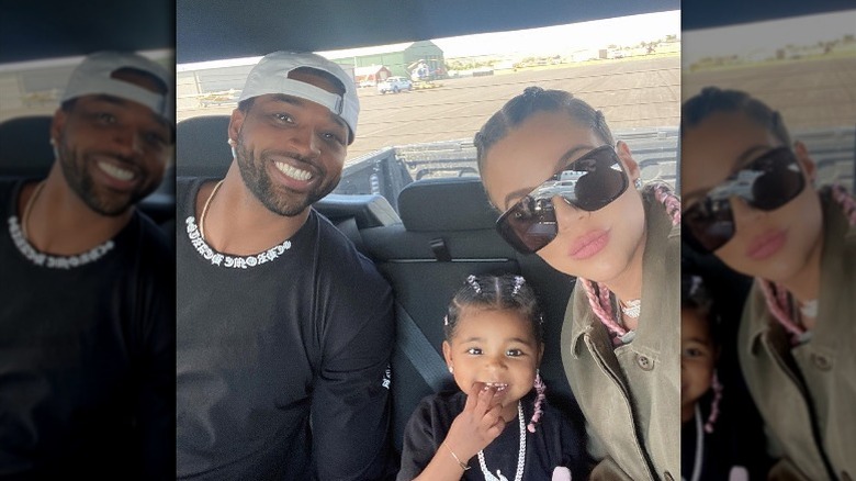 Tristan Thompson and Khloé Kardashian smiling in the backseat with their daughter True