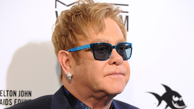 Elton John poses in blue glasses