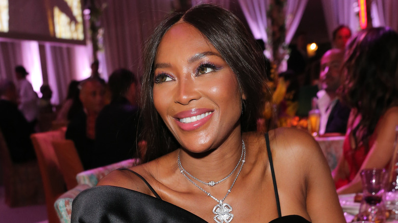 Naomi Campbell smiles while seated at a table