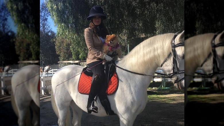 Lisa Vanderpump on a horse with one of her pups