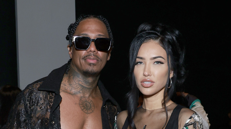 Nick Cannon and Bre TIesi stand together at event