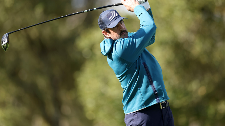 Aaron Rodgers swinging a club on golf course