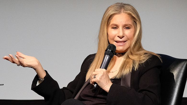 Barbra Streisand with microphone in hand, speaking