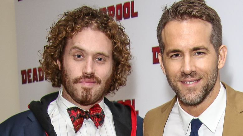 TJ Miller wearing a blue jacket, white shirt and red bowtie with Ryan Reynolds wearing a tan suit and white shirt