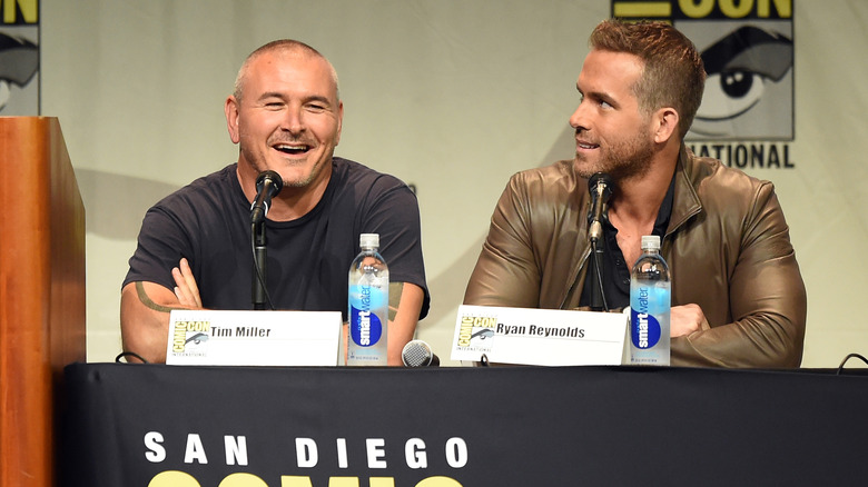 Tim Miller wearing a black t-shirt and Ryan Reynolds wearing a brown leather jacket