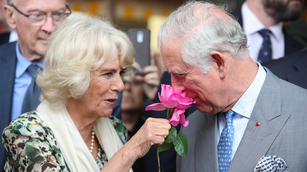 Camilla Duchess of Cornwall holding a flower for Prince Charles to smell