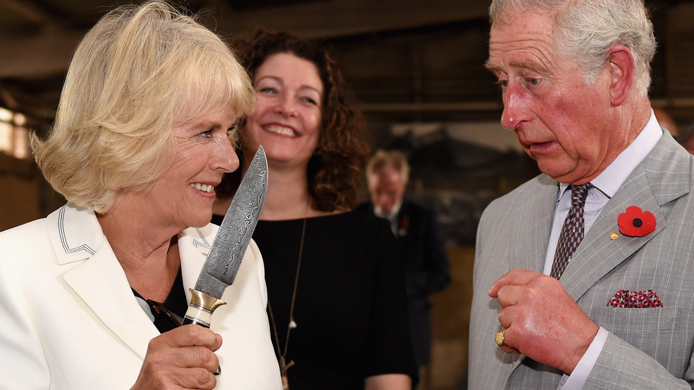 Camilla Duchess of Cornwall jokingly wielding a knife at Prince Charles