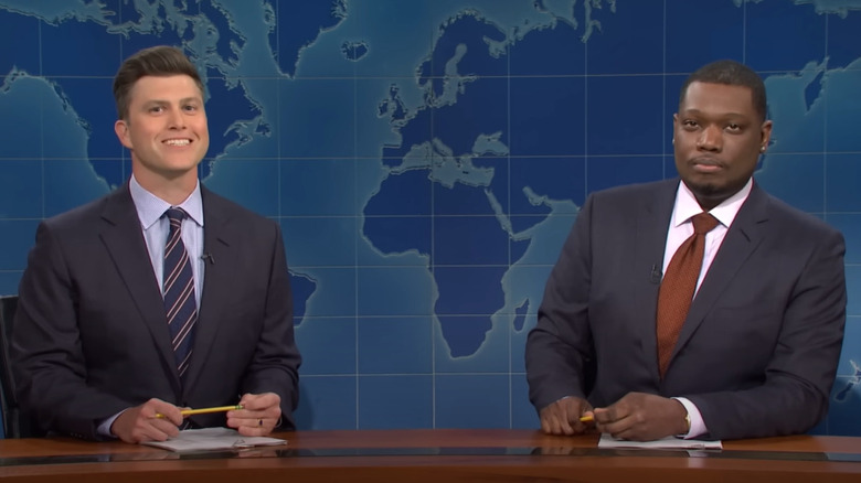 Colin Jost, Michael Che seated at desk